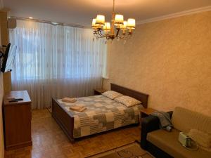 a bedroom with a bed and a couch and a chandelier at Помірецька,9 in Truskavets