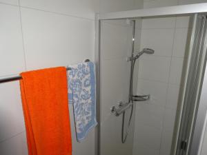 ducha con toalla naranja y puerta de cristal en Ferienwohnung Casa Ursina, en Sedrun