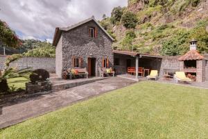 a stone house with a yard with a grassy lawn at Casa da Pedra in Santana