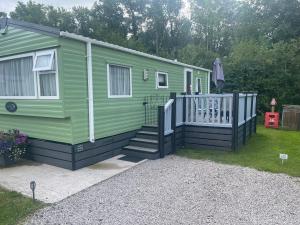 une petite maison verte avec une terrasse couverte et des escaliers dans l'établissement 4 lakes holiday let, à Carnforth