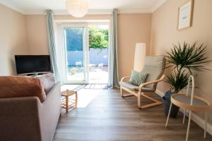 a living room with a couch and a tv at Cosy Brixham apartment with garden close to Town in Brixham