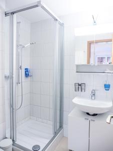 a white bathroom with a shower and a sink at Studio Omis in Zermatt