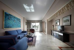 un salon avec un canapé bleu et une télévision dans l'établissement Hotel Abades Benacazon, à Benacazón