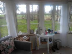a living room with windows and a couch and a table at Romantik og idyl in Dybvad