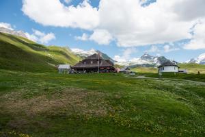 ein Haus auf einem Feld mit Bergen im Hintergrund in der Unterkunft Berggasthaus Tannalp in Frutt