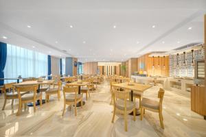 a dining room with wooden tables and chairs at Holiday Inn Express - Harbin Songbei New District, an IHG Hotel in Harbin