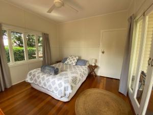 a bedroom with a bed and two windows at Miss Bullens Cottage in Yungaburra