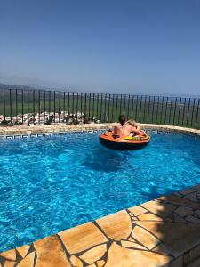 para ludzi jeżdżących pomarańczową tratwą w basenie w obiekcie Villa Luz del Monte w mieście Denia