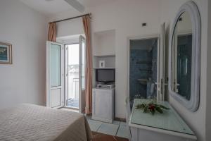 um quarto com uma cama, uma televisão e uma janela em Hotel Gennarino A Mare em Ponza