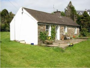 ein kleines Steinhaus auf einem Grasfeld in der Unterkunft Cottage by the Sea, West Cork, Ireland in Kilbrittain