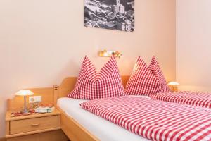 1 dormitorio con 2 camas y almohadas rojas y blancas en Haus Schwaighofer, en Saalbach Hinterglemm