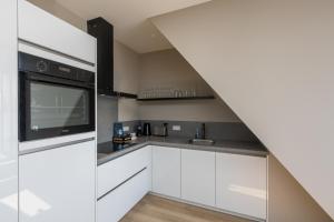 une cuisine avec des armoires blanches et un appareil noir dans l'établissement Luxe appartement Ooststraat 8b, à Domburg
