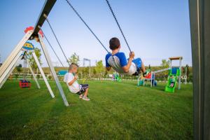 deux jeunes garçons jouant sur des balançoires dans un parc dans l'établissement Fracanzana Hotel, à Montebello Vicentino