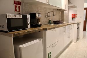 a kitchen with white cabinets and a microwave on a counter at Barreiro Central Apartment in Barreiro