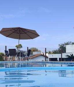een zwembad met een tafel en een parasol en stoelen bij Rancho Paraíso in Capitólio