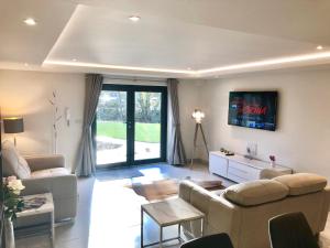 a living room with two couches and a tv at Millstream Mews in Bakewell