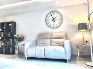 a living room with a couch and a clock on the wall at Millstream Mews in Bakewell