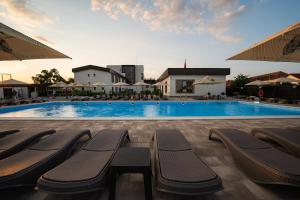 ein großes Schwimmbecken mit Bänken und Sonnenschirmen in der Unterkunft Hotel River in Luduş