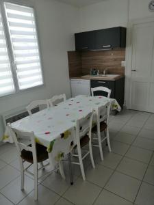 a kitchen with a white table and chairs with a table and a kitchen at Gîte en Brenne Les Chênes in Mérigny
