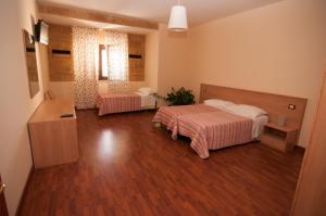 una camera da letto con due letti e pavimento in legno di Albergo Conca D'Oro a Foggia