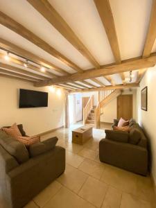 a living room with two couches and a flat screen tv at The Barn in Bedale