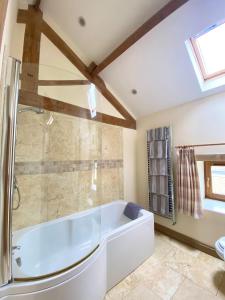 a bathroom with a white tub and a shower at The Barn in Bedale