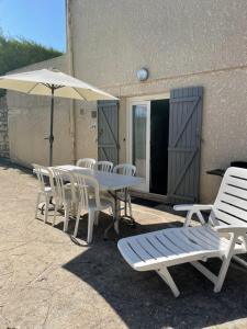 eine Terrasse mit einem Tisch, Stühlen und einem Sonnenschirm in der Unterkunft 61 BIS ST GEORGES DE DIDONNE in Saint-Georges-de-Didonne