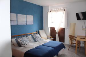 Un dormitorio con una cama con paredes azules y una mesa. en Apartamentos Playa, en Hermigua