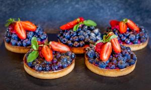 four pieces of bread with fruit and strawberries on top at Hôtel 3 étoiles -Restaurant Le Pilatus Courchevel in Courchevel