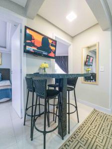a kitchen with a bar with stools and a tv on the wall at Apartamento Pontal Norte Ao Lado Da Big Wheel in Balneário Camboriú