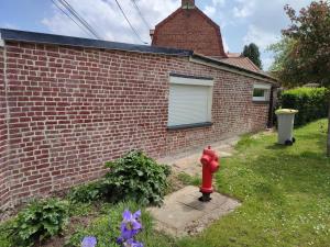 una boca de incendios roja frente a una casa de ladrillo en Charmante petite maison cosy style industriel, en Longuenesse