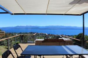 a table and chairs on a deck with a view of the water at Ventanas Al Lago in San Carlos de Bariloche