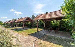 un grupo de refugios de picnic con bancos en un parque en Apartmány Karmon Park en Veľký Meder