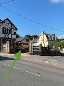 a green arrow pointing to a house on a street at Union Road Moto Velo Accommodation in Crediton