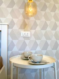 a table with two cups on it with a wall at Le Calette House - Puglia Mia Apartments in Monopoli