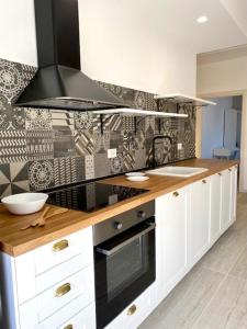 a kitchen with white cabinets and a black stove top oven at Le Calette House - Puglia Mia Apartments in Monopoli