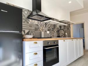 a kitchen with white cabinets and a black stove top oven at Le Calette House - Puglia Mia Apartments in Monopoli