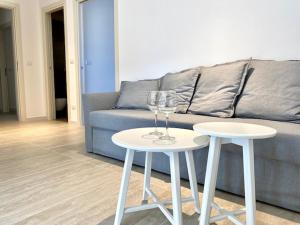 two white tables in front of a couch with wine glasses at Le Calette House - Puglia Mia Apartments in Monopoli