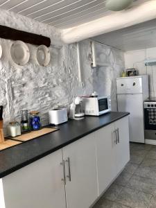 uma cozinha com armários brancos e um micro-ondas branco em Thistle Cottage Alojamento Local em Gatas