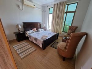 ein Schlafzimmer mit einem Bett, einem Stuhl und einem Fenster in der Unterkunft Srinagar Homes in Muzaffarabad