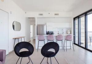 uma cozinha com cadeiras cor-de-rosa e pretas num quarto em O&O Group- Modern Luxury APT-Mesmerizing Sea Views em Bat Yam