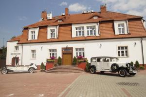 two old cars parked in front of a white house at Pałacyk w Pakości Hotel in Pakość