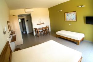 a room with two beds and a table and chairs at Domatia me Thea in Elafonisos