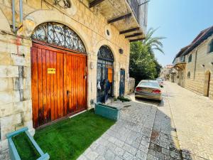 a building with a wooden door and a car on a street at Zimmer in old City in Safed