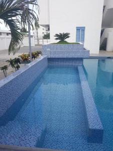 a blue tile swimming pool with a palm tree at COMODO DEPARTAMENTO CERCA DE LA PLAYA WIFFI in Tonsupa