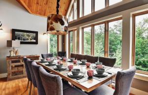 a dining room with a table and chairs and windows at Chalets Alpins - 56 Chemin des Skieurs in Stoneham