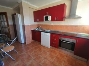 kuchnia z czerwonymi szafkami, zlewem i kuchenką w obiekcie Apartamento Juan Bautista w Maladze +8 zdjęć