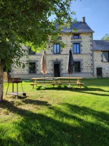 zwei Picknicktische und Sonnenschirme vor einem Gebäude in der Unterkunft Gîte Lepetit Sabotier grande capacité Puy de Dôme in Giat