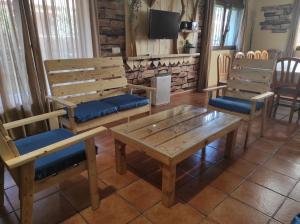 Los Alisos Casa Rural في غواداليكس دي لا سييرا: غرفة بها مقاعد خشبية وطاولة وكراسي