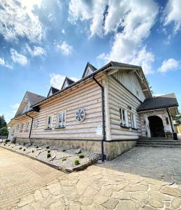 a large wooden building with a stone driveway at Karczma Kubalonka in Istebna